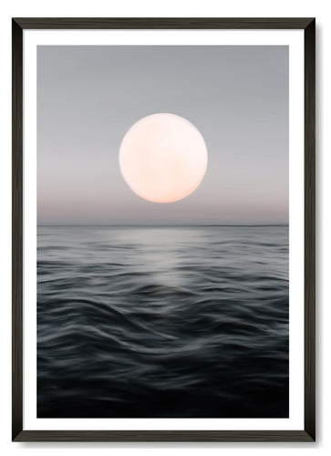 Full moon reflecting over the sea at night displayed in a black frame